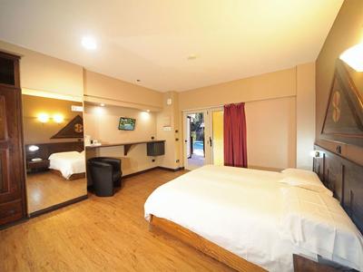 Helles Schlafzimmer mit Doppelbett, Holzfußboden, Schrank mit Spiegeltüren und Sesseln.