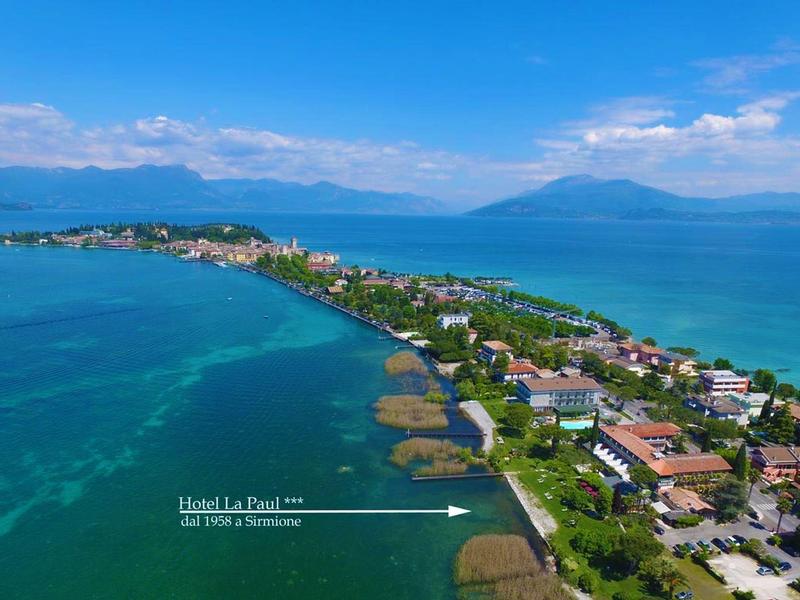 Langer schmaler Landstreifen mit Häusern, blauem Meer links und rechts, Bergen im Hintergrund.