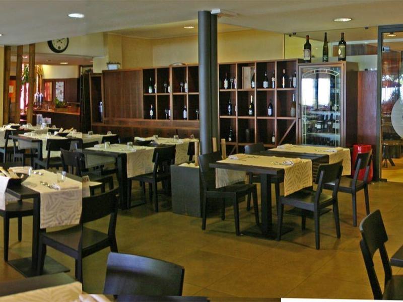 Weitläufiges Restaurant mit Holz- und hellen Möbeln, gedeckten Tischen und warmem Licht.