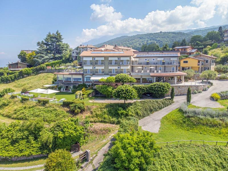 Grande edificio di hotel su una collina verde con sentieri circostanti e vista sulle montagne.