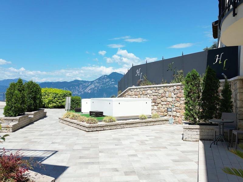 Area terrazza moderna dell'hotel con poltrone lounge, vista sulle montagne e cielo blu.