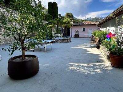 Cortile con piante in vaso, mobili da giardino bianchi e cielo azzurro con nuvole