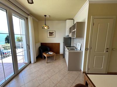 Piccola angolo cottura con zona salotto e vista sul balcone in una camera d'hotel.