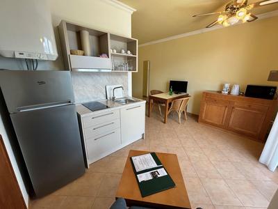 Piccola angolo cottura con frigorifero, microonde e tavolo da pranzo in una stanza luminosa.