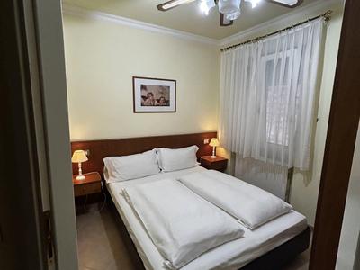 Camera d'hotel accogliente con letto matrimoniale, comodini, ventilatore a soffitto e finestra con tende.