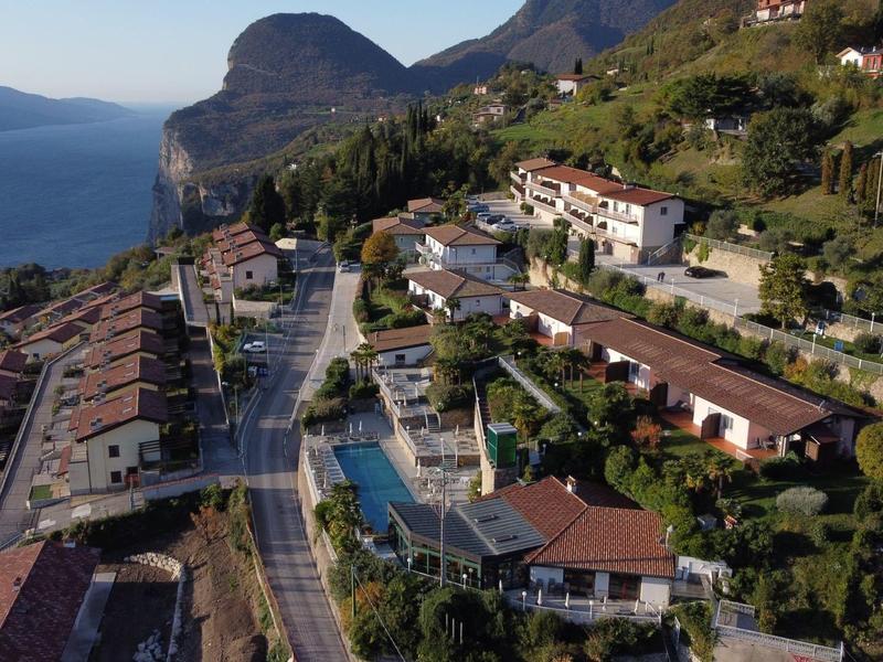 Vista di un paese costiero con case, una piscina e montagne sullo sfondo.