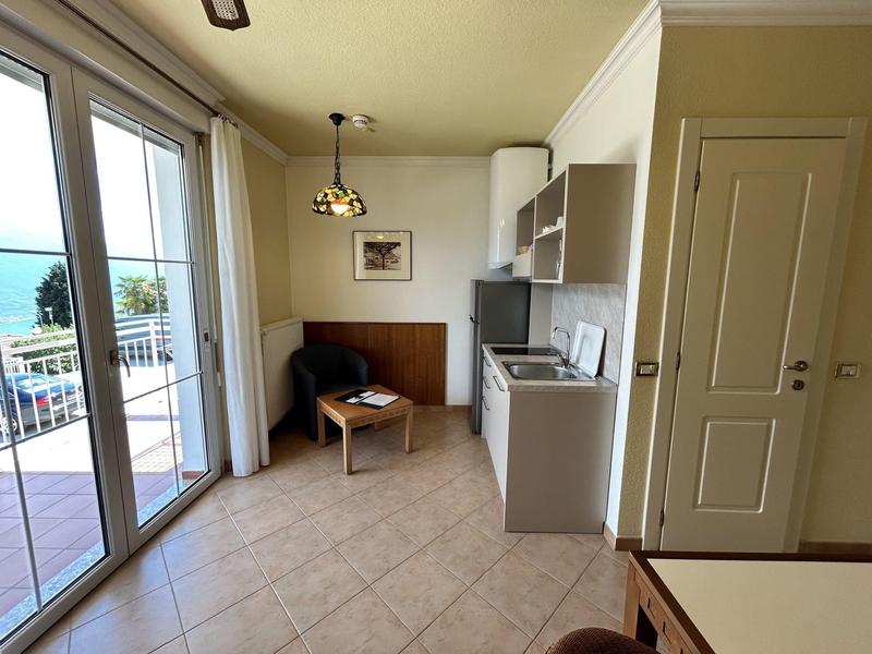 Piccola angolo cottura con zona salotto e vista sul balcone in una camera d'hotel.