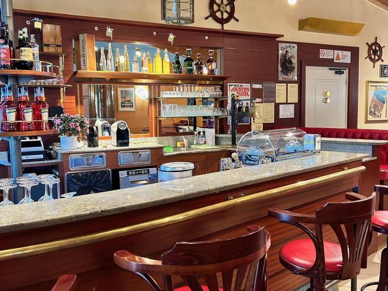 Bar accogliente in stile legno con sgabelli rossi e luci a soffitto.