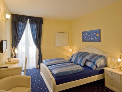 Chambre d'hôtel confortable avec lit double, tapis et rideaux bleus, murs jaunes et balcon.