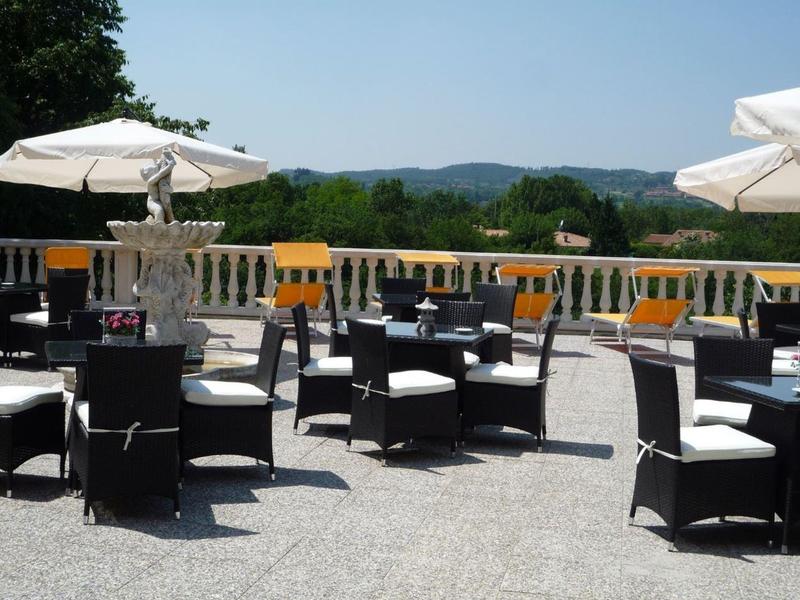 Terrasse extérieure avec sièges noirs et parasols blancs, vue sur des collines verdoyantes.