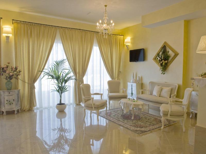 Salon lumineux et élégant avec meubles crème, grands rideaux et lustre.