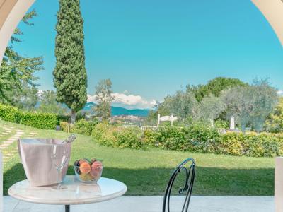 Vista a través de un arco hacia una mesa con enfriador de vino y copas frente a un paisaje verde.