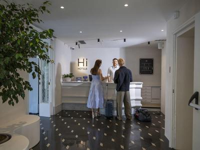 Receptie in modern hotel met gasten bij balie, lichte muren en planten