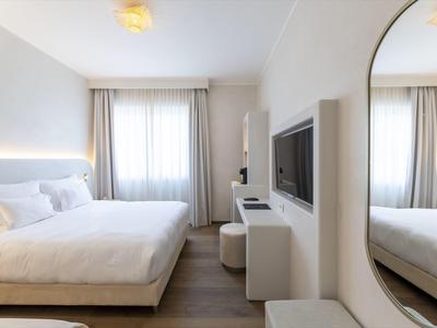 Habitación de hotel moderna con cama grande, TV y espejo en la pared.