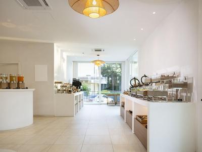 Sala de desayuno luminosa y moderna con buffet y gran ventana hacia el exterior.