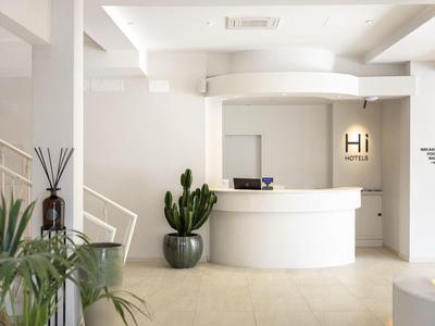 Heller, moderner Hotellobby mit rundem weißen Empfangstresen und großen grünen Pflanzen.