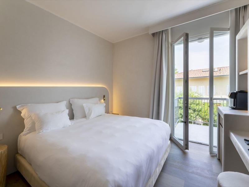 Dormitorio moderno con cama doble grande y balcón con vistas.