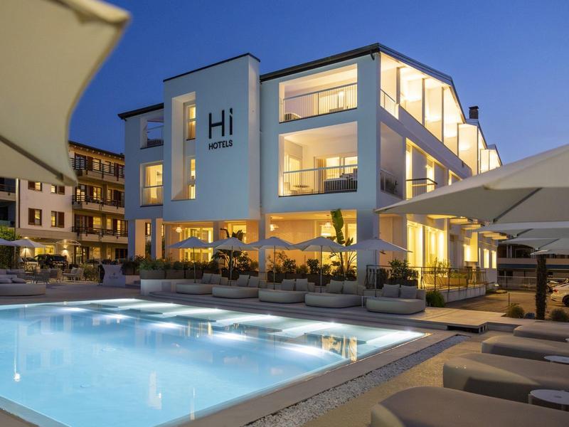 Edificio de hotel moderno con piscina iluminada y tumbonas por la noche