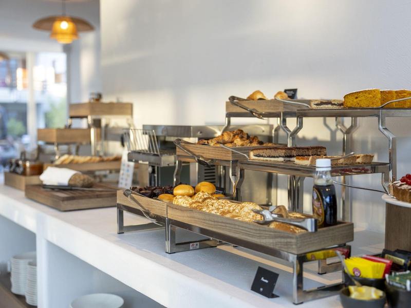 Bufé con panecillos frescos, pasteles y mermeladas en una sala de desayuno luminosa.