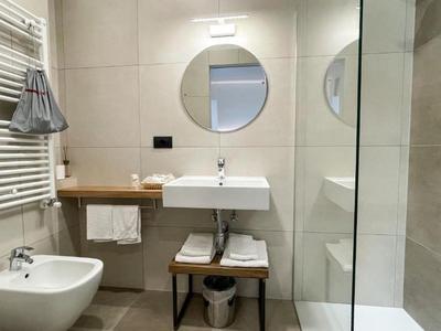 Modernes Badezimmer mit Waschbecken, Bidet, Badewanne und rundem Spiegel.