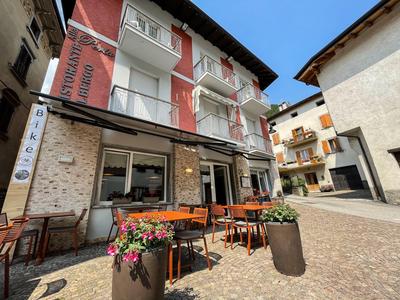 Außenbereich eines Hotels mit Tischen, Stühlen und Blumen in Pflanzgefäßen auf Kopfsteinpflaster.