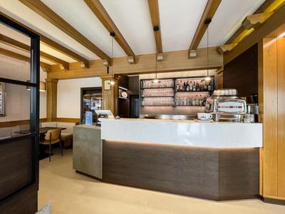 Moderner Hotel-Barbereich mit Holzdeckenbalken und beleuchtetem Tresen.