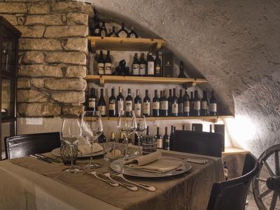 Elegantes Restaurant mit Weinen in Steinraum und gedecktem Tisch.