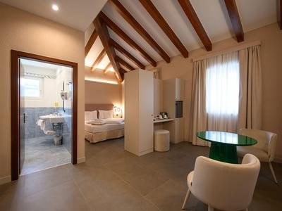 Schlicht eingerichtetes Hotelzimmer mit Sitzbereich und angrenzendem Badezimmer.