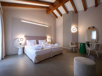 Modernes Hotelzimmer mit Doppelbett, Sofas und rustikalem Holzbalken an der Decke.