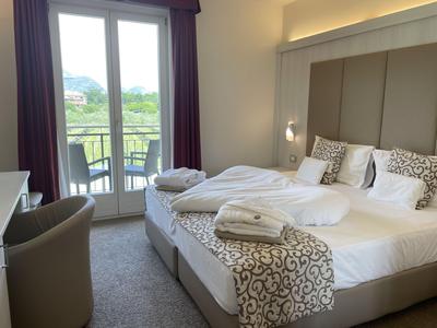 Elegantes Hotelzimmer mit Doppelbett, Balkon und Blick auf grüne Landschaft.