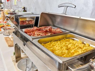 Bufet s míchanými vejci, slaninou a různými snídaňovými produkty v hotelu.