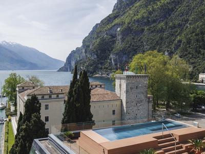 Hotelanlage mit Pool, Blick auf See und Berge an einem bewölkten Tag.