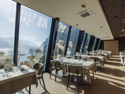 Modernes Restaurant mit großen Fenstern und Blick auf Berge und See.