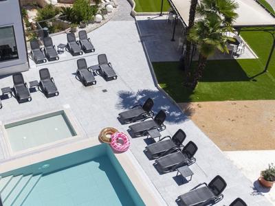 Hotelpool mit Sonnenliegen, aufwendig angelegte Gartenflächen und schattige Pavillons.