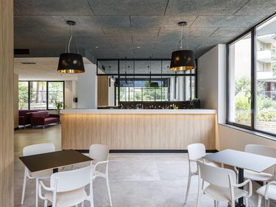 Moderner Hotel-Loungebereich mit Bar, weißen Stühlen und großen Fenstern