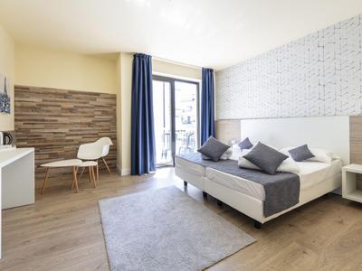Helles Hotelzimmer mit Doppelbett, Sitzbereich und großem Fenster mit Blick nach draußen.