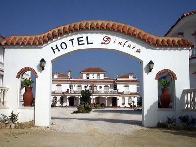 Biały budynek hotelu z czerwoną dachówką za łukiem z napisem 'Hotel D'jarla'.