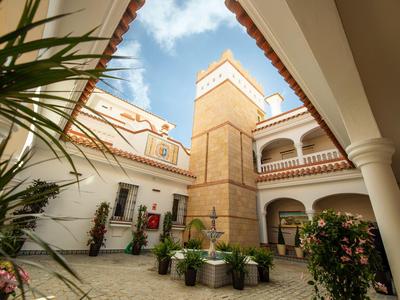 Patio de hotel con plantas, estructura de torre y cielo azul.