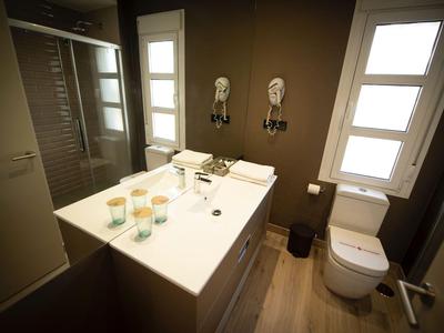 Nowoczesna łazienka hotelowa z jasną umywalką, toaletą i dużymi lustrami.