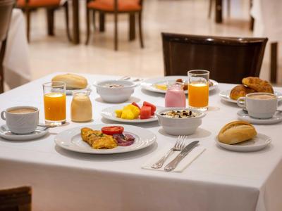 Ein gedeckter Frühstückstisch mit Kaffee, Saft, Obst, Brötchen und Aufschnitt in einem Restaurant.