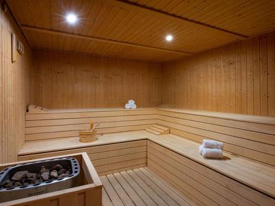 Innenansicht einer Sauna mit Holzbänken, einem Saunaofen und Handtüchern.