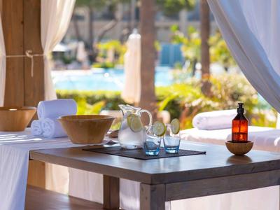 Ein Holztisch mit Wassergläsern, Karaffe und Schalen in einer offenen Lounge am Pool.