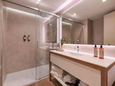 Modernes Badezimmer mit begehbarer Dusche, großem Spiegel und Waschtisch mit Handtüchern.