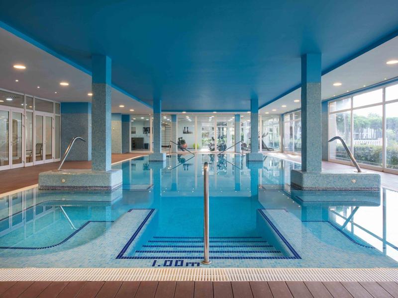 Modernes Hallenbad mit Pool, Whirlpool und großen Fenstern für Tageslicht.