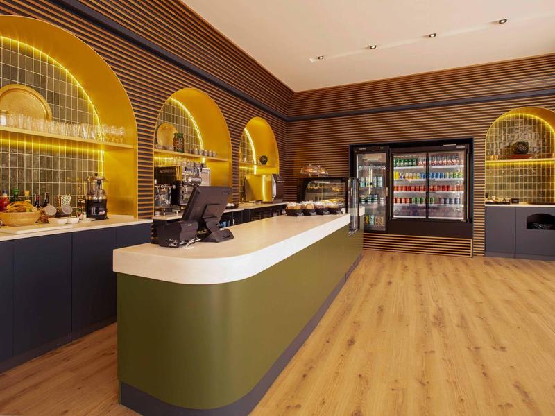 Moderne Hotelbar mit geschwungenem Tresen, Holzfußboden und beleuchteten Regalen.