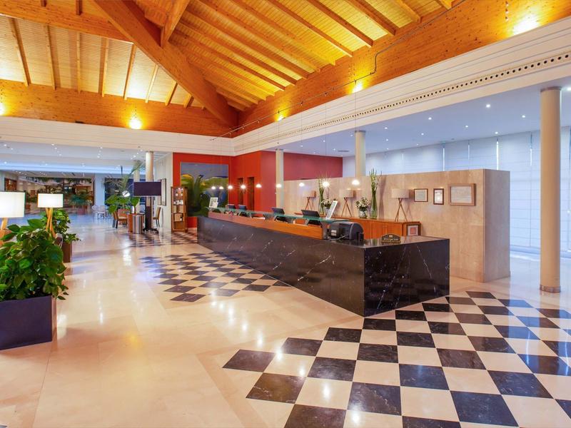 Moderner Hotel-Lobbybereich mit riesiger Theke und schwarz-weiß kariertem Boden.