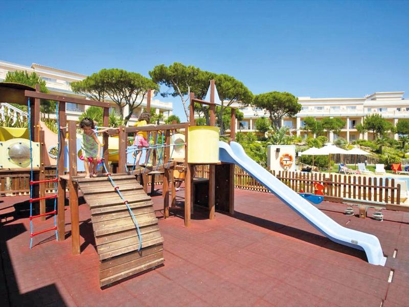 Kinderspielplatz mit Klettergerüst und Rutsche in Hotelanlage bei Sonnenschein