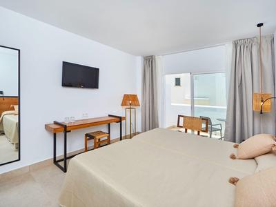Helles Schlafzimmer mit Doppelbett, Schreibtisch, Fernseher, Spiegel und Balkon mit Sicht aufs Meer.