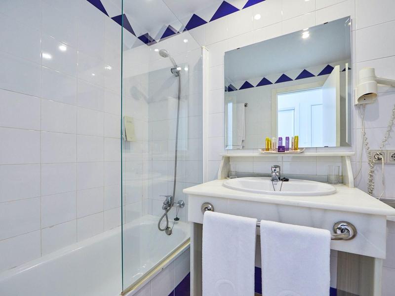 Moderne Hotelbadezimmer mit Dusche, Waschbecken, großem Spiegel und Handtüchern.