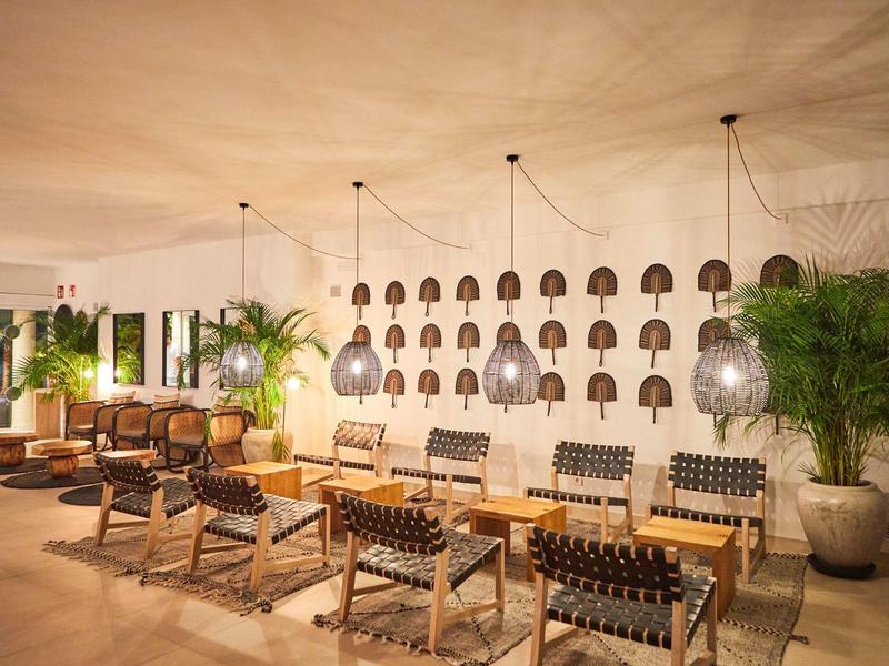 Heller, moderner Hotel-Lounge-Bereich mit Ledersesseln, Hängelampen und Wanddekoration.